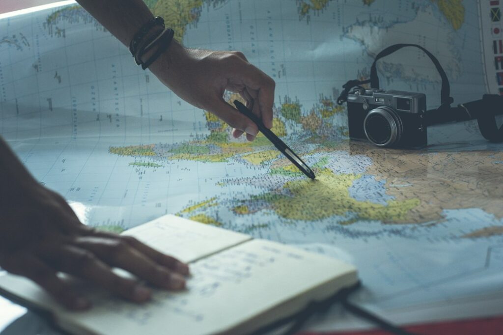 World map, notes and pencil for itinerary planning; illustrative stock photograph, not TransferHub fleet or an actual pickup point